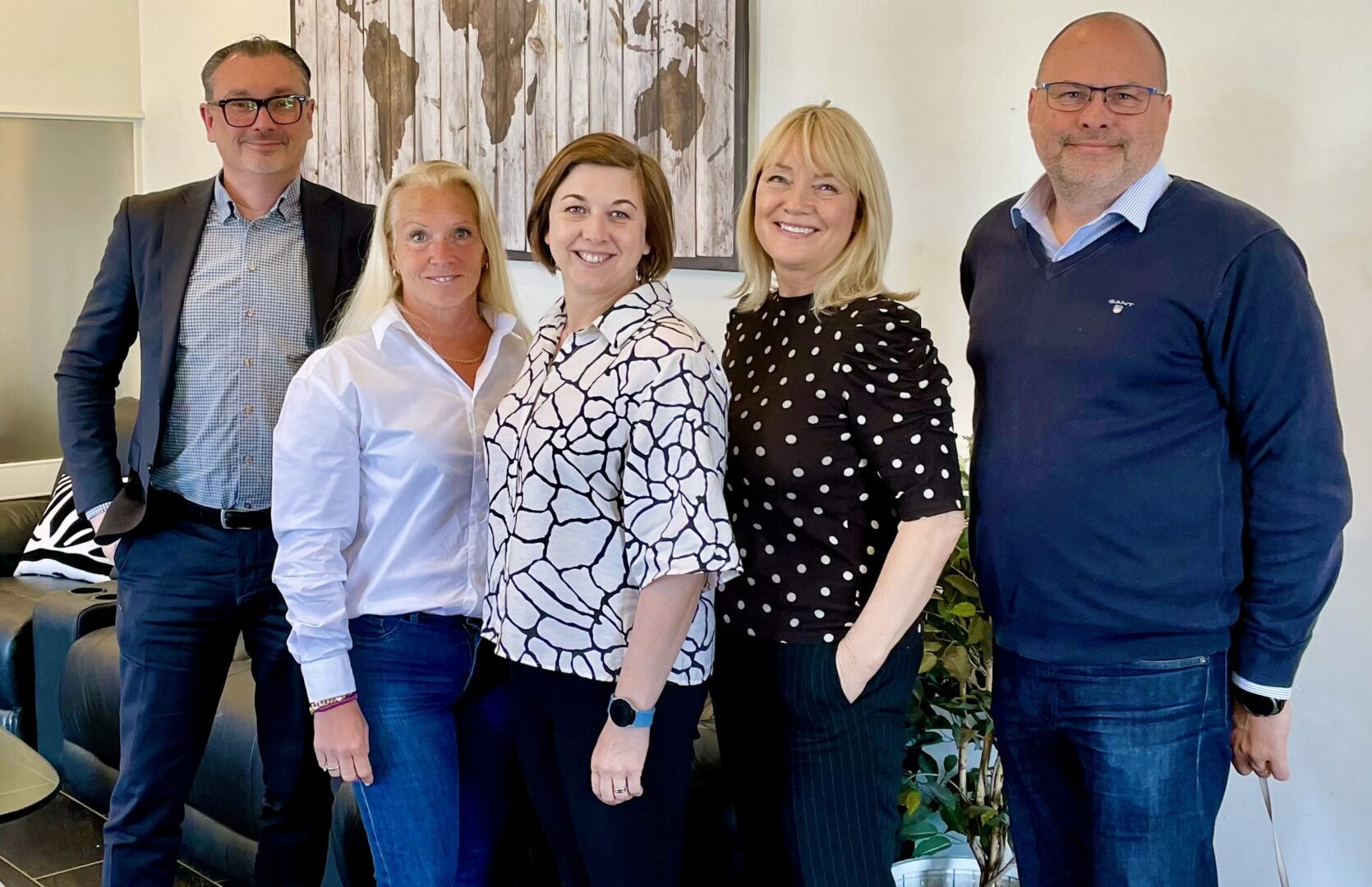 Två män och tre kvinnor står uppställda framför en soffa.